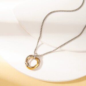 A necklace with three rings interlocked together in gold and silver